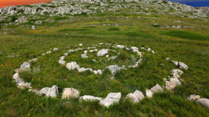 Rocky spiral design on a grassy hillside with scattered