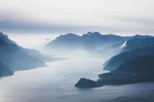Misty lake surrounded by mountains and hills on a cloudy