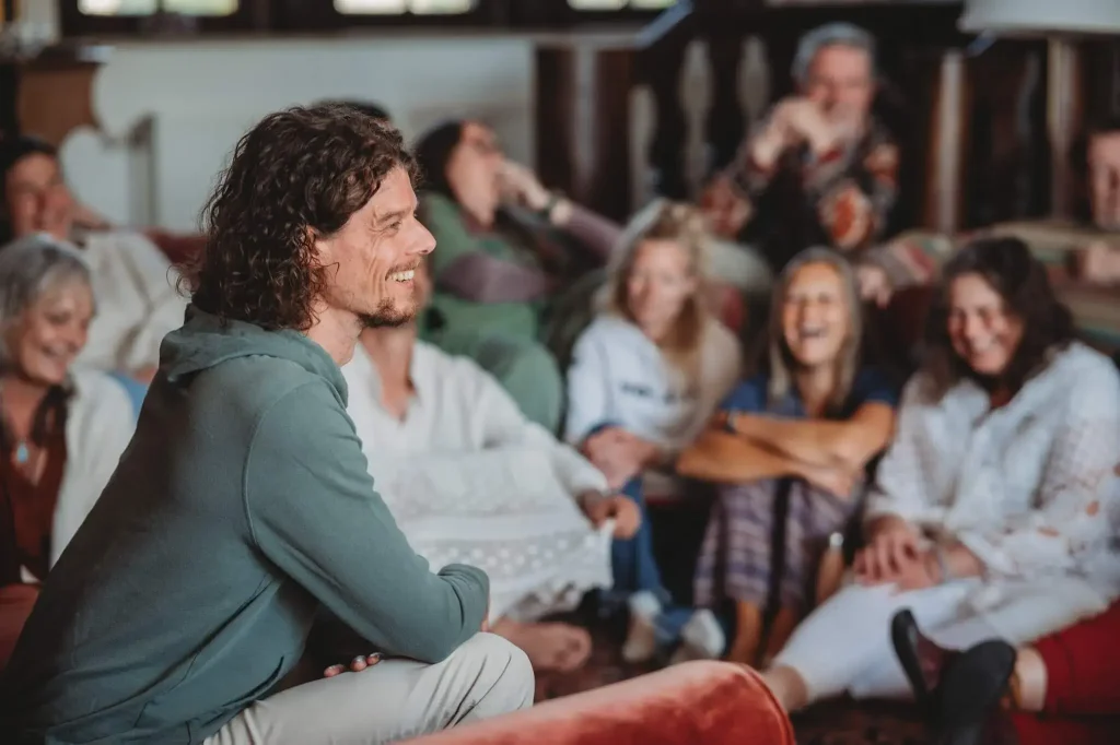 Man with curly hair sitting on couch, smiling at